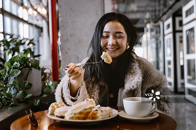 中国女孩在餐厅吃松饼喝咖啡图片素材