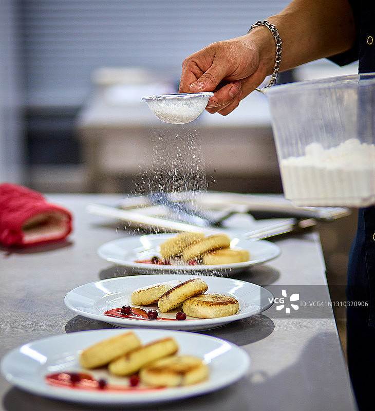 厨师在厨房里为甜点撒上糖粉，侧视图图片素材