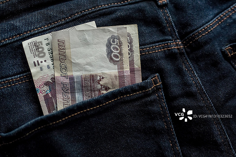 口袋里的钱。俄罗斯卢布。裤子口袋里500卢布的钞票。牛仔裤，口袋里的钱。商业、贸易或金融交易，欺诈、腐败和贿赂。近距离图片素材