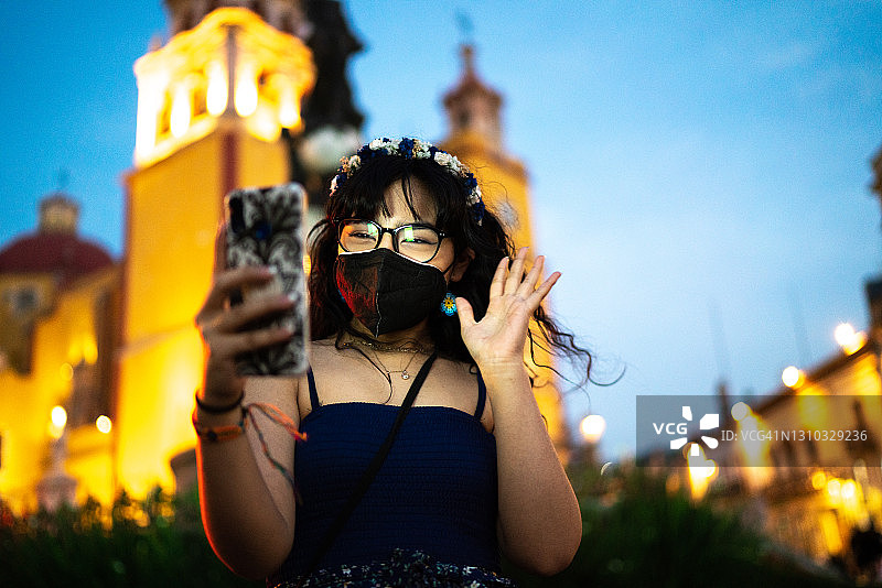 戴口罩的少女在户外用手机进行视频通话图片素材