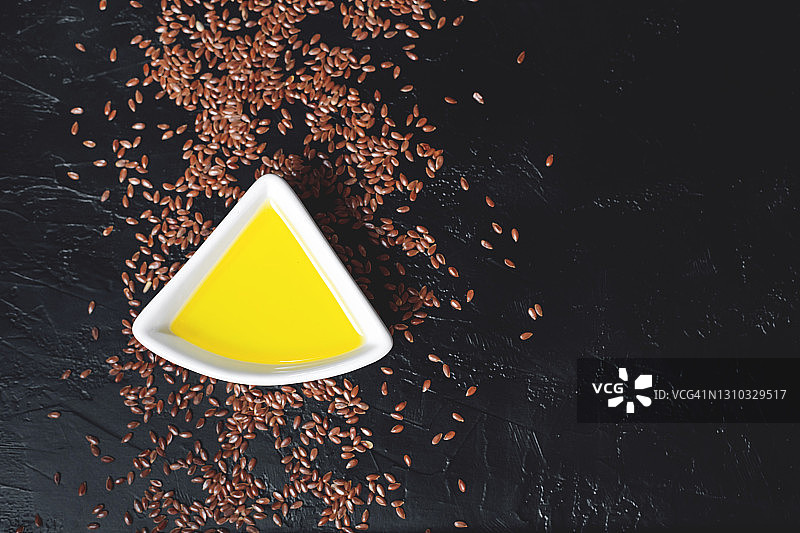 亚麻籽与亚麻籽油：白色碗和玻璃瓶，深色背景图片素材