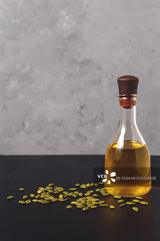 白色碗中的南瓜籽与深灰色背景上的南瓜籽油图片素材
