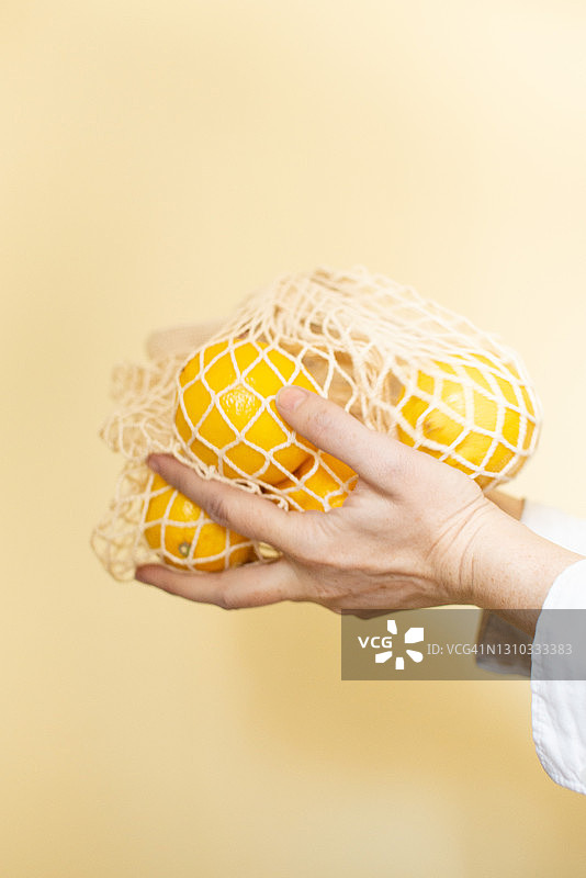 黄色纸背景上环保网格中的黄色柠檬图片素材