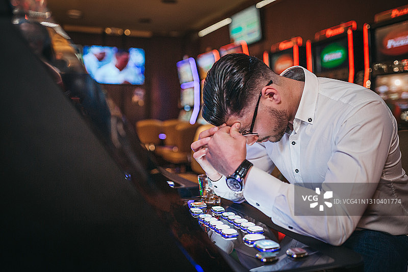 在老虎机上输钱的年轻男人图片素材