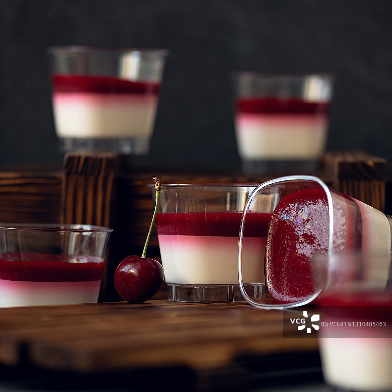 杯装慕斯牛奶樱桃甜点（深色背景，红色浆果冻，侧视）图片素材