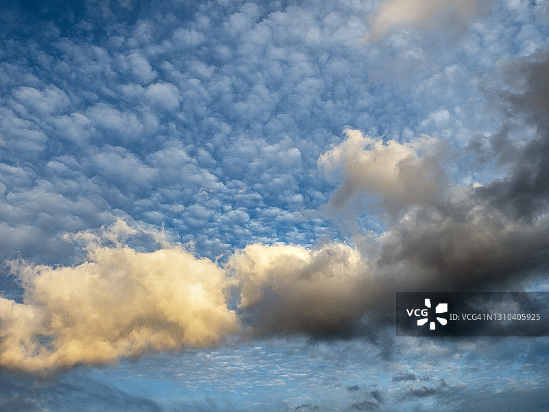 日落时阳光照耀下的蓝色天空和橙色云彩图片素材