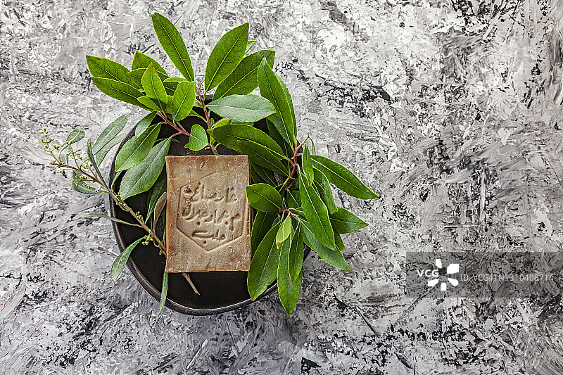 阿勒颇硬皂，叙利亚传统产品，灰色背景下的月桂和橄榄枝皂碟图片素材