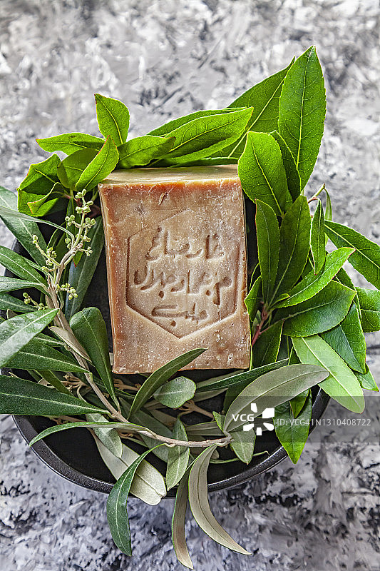 阿勒颇硬皂，叙利亚传统产品，灰色背景下的月桂和橄榄枝皂碟图片素材