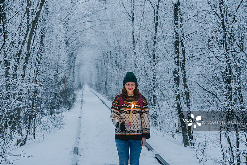 冬季手持烟花蜡烛站在爱情隧道里的女人图片素材