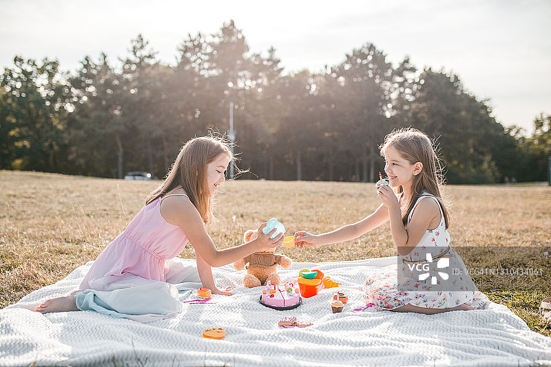 姐妹俩在野餐时玩玩具，举办茶话会图片素材