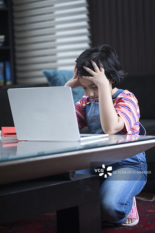 女孩使用笔记本电脑做作业时感到压力大图片素材