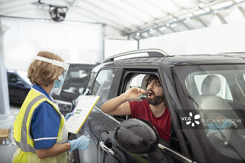 男子在汽车穿梭新冠检测中心使用拭子采样图片素材