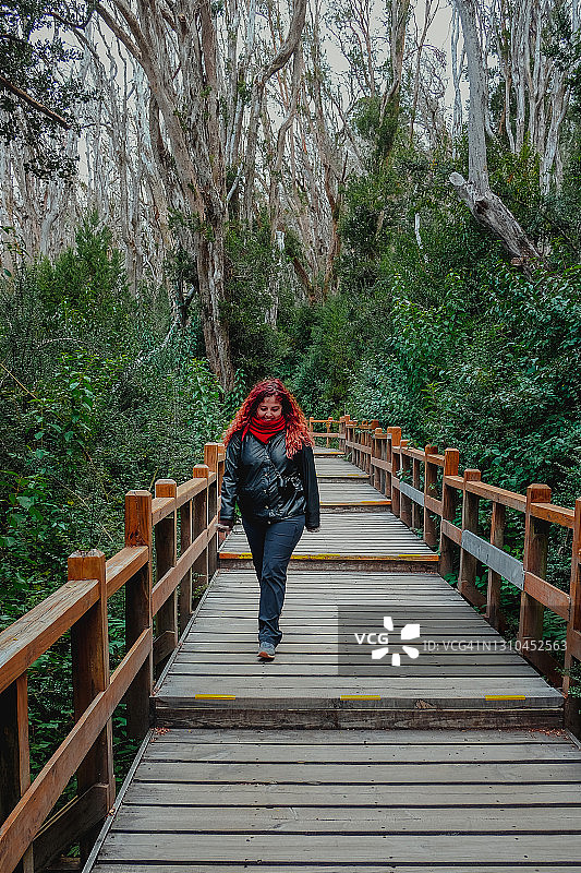 在Arrayan森林入口楼梯上行走的红发徒步女性图片素材