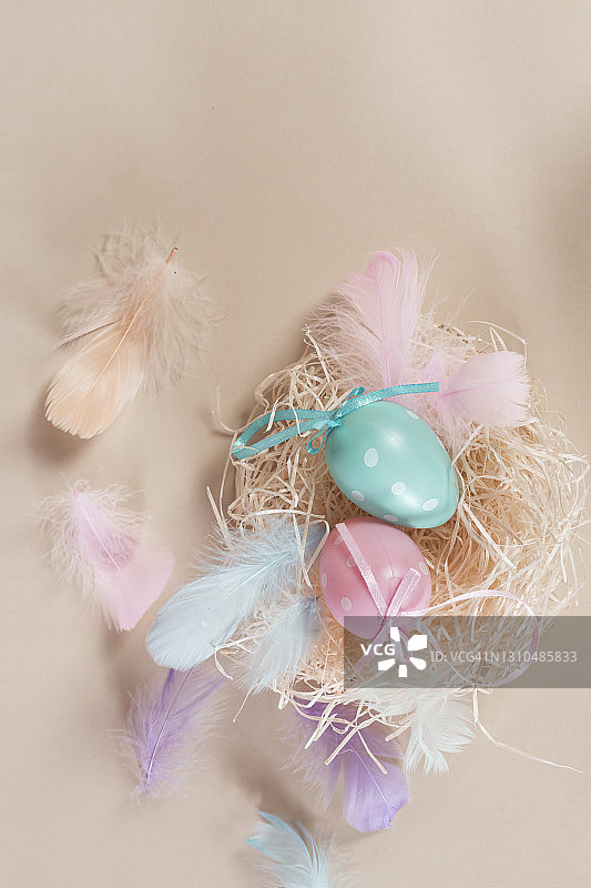 米色背景下的鸟巢和羽毛中的彩色复活节彩蛋图片素材