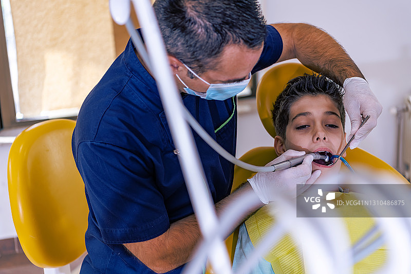 害怕的孩子张着嘴坐在牙医的椅子上图片素材
