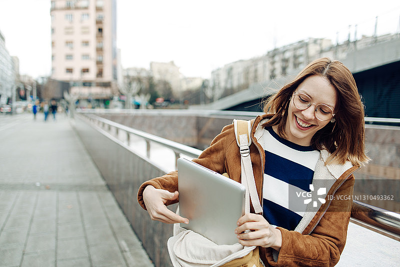 从包里拿出笔记本电脑的美丽女学生肖像图片素材