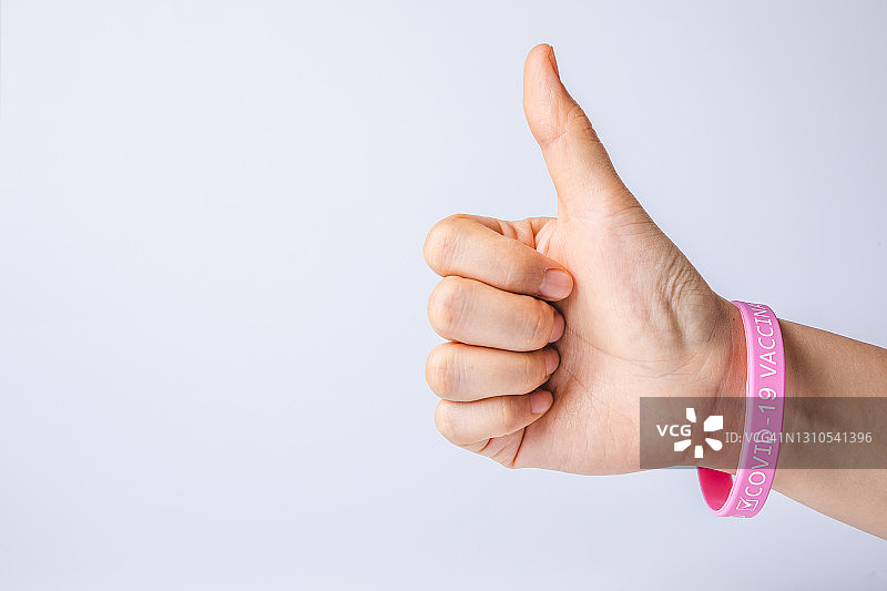 佩戴“已接种COVID-19疫苗”腕带的点赞手势图片素材