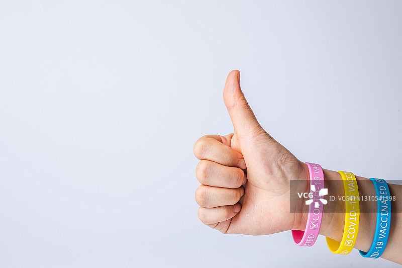 佩戴“已接种COVID-19疫苗”腕带的点赞手势图片素材