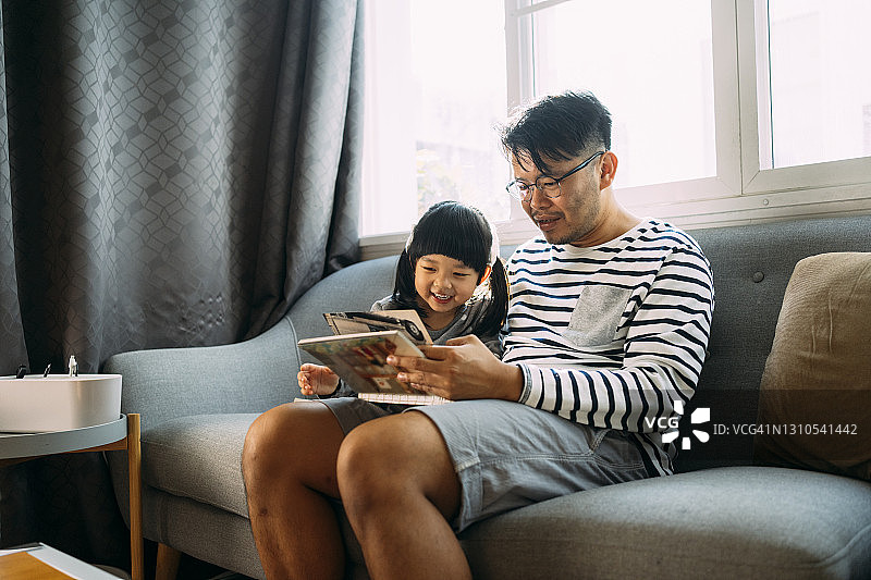 父亲在家与女儿共度美好时光阅读书籍周末活动图片素材