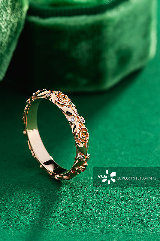 绿色背景上花卉设计的玫瑰金钻石戒指图片素材