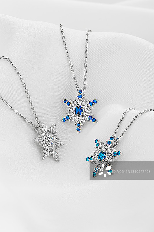 白色背景上的三个银色雪花项链吊坠图片素材
