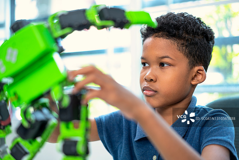 非洲裔男孩组装机器人套件并在学校计算机编程课上进行编程图片素材