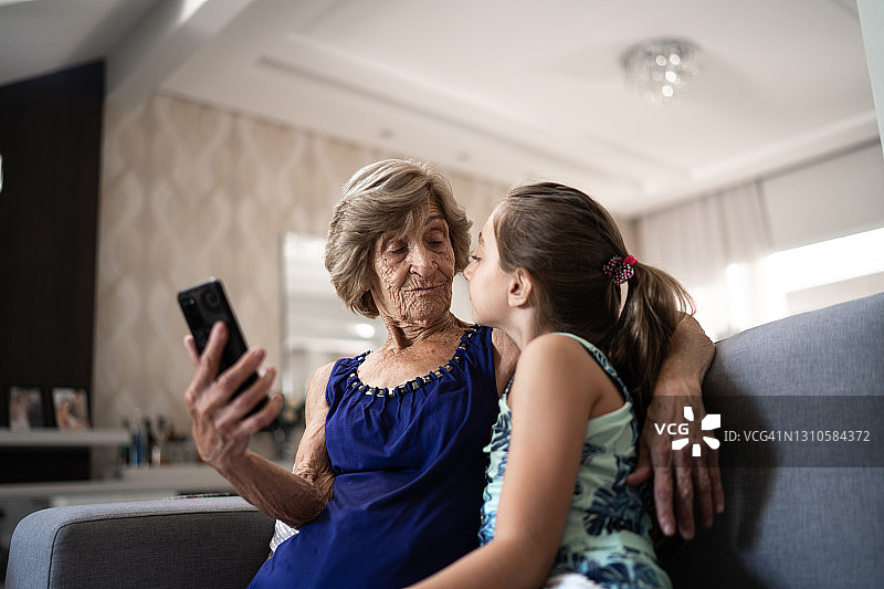 女孩在家用手机与祖母自拍图片素材