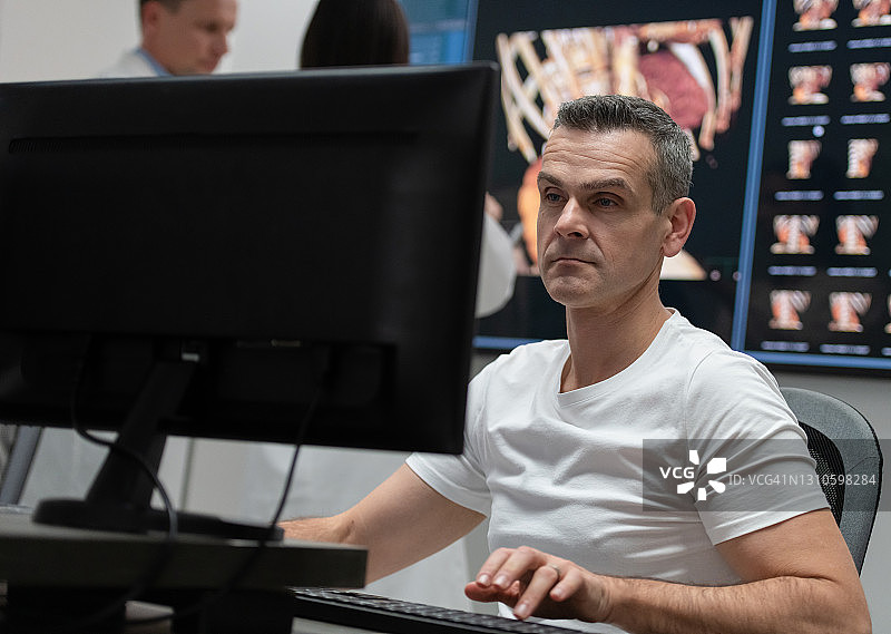 男放射科医生在控制室查看核磁共振扫描结果图片素材