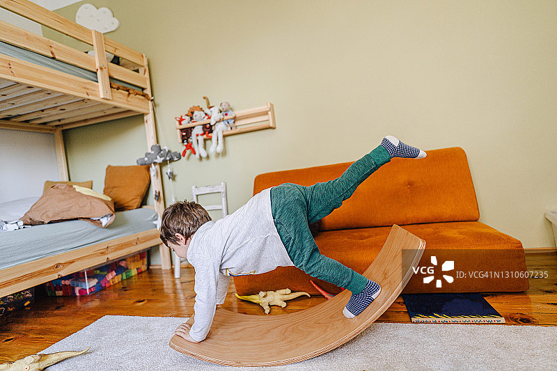 小男孩在房间里玩平衡板图片素材
