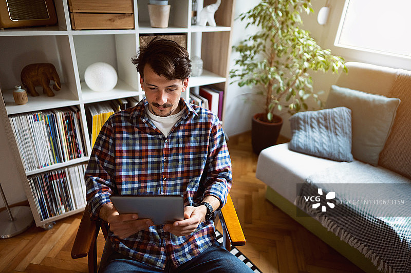 在家放松并使用平板电脑的年轻白人男子图片素材