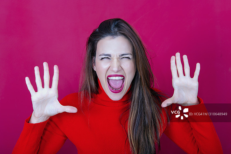 举起双手，手掌朝前，张开嘴巴尖叫的年轻女人图片素材