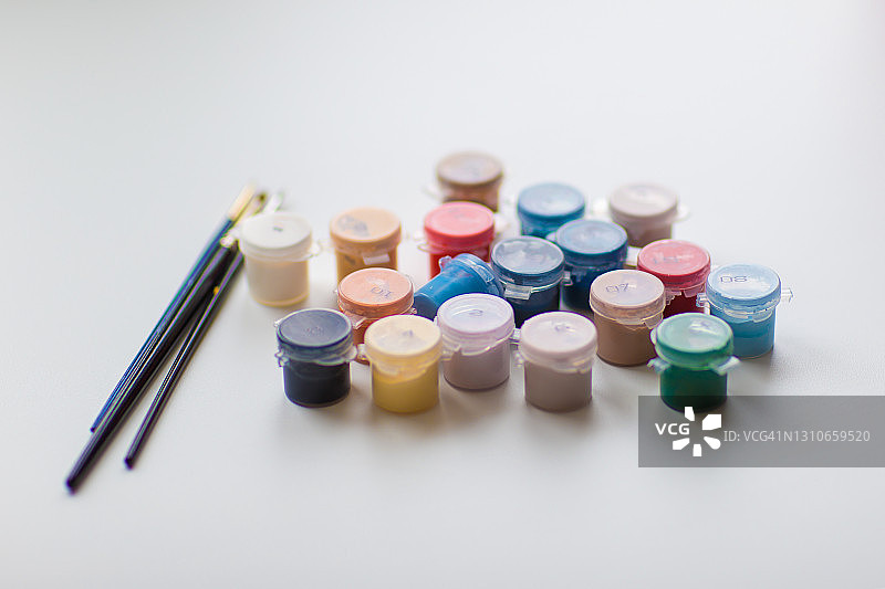 白色背景上的彩色颜料罐和画笔图片素材