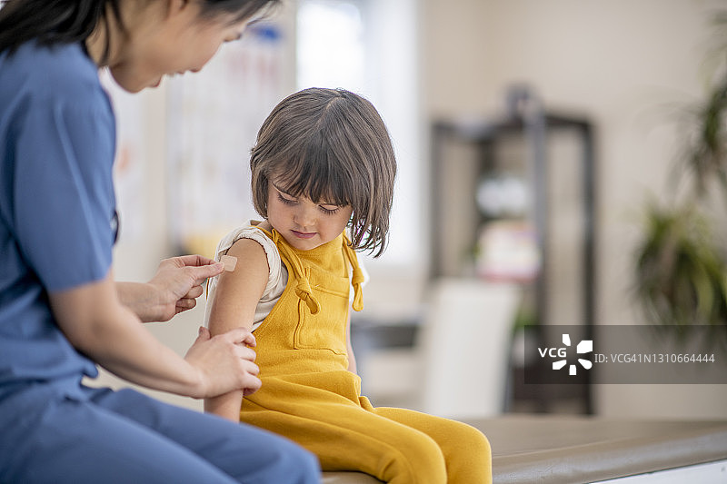 女护士为小女孩手臂贴创可贴图片素材