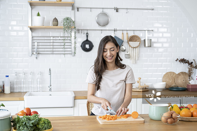 美丽的女人在厨房里切菜准备食材图片素材