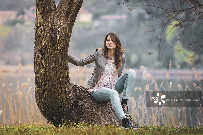 年轻女人坐在意大利伦巴第莱科省奇瓦泰的树干上图片素材