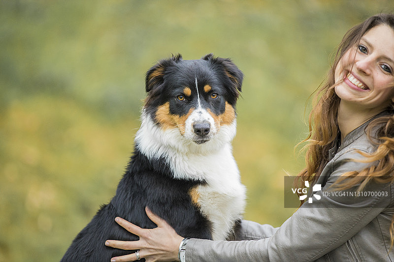 年轻女人抱着澳洲牧羊犬微笑图片素材