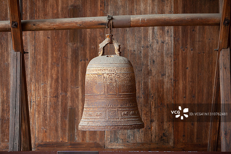 木墙上悬挂着一个生锈的铃铛图片素材