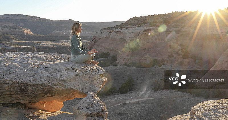 年轻女人在岩脊上放松做瑜伽图片素材