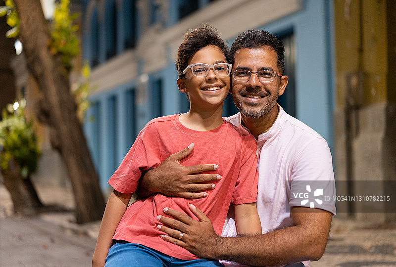 父子坐在公园长椅上图片素材