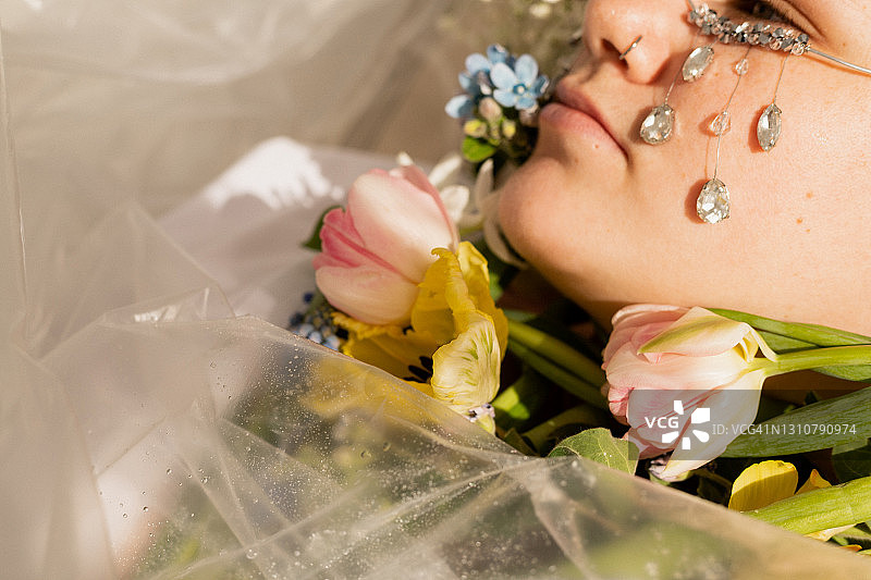 鲜花和塑料薄膜中哭泣的女人与水晶的局部拍摄图片素材