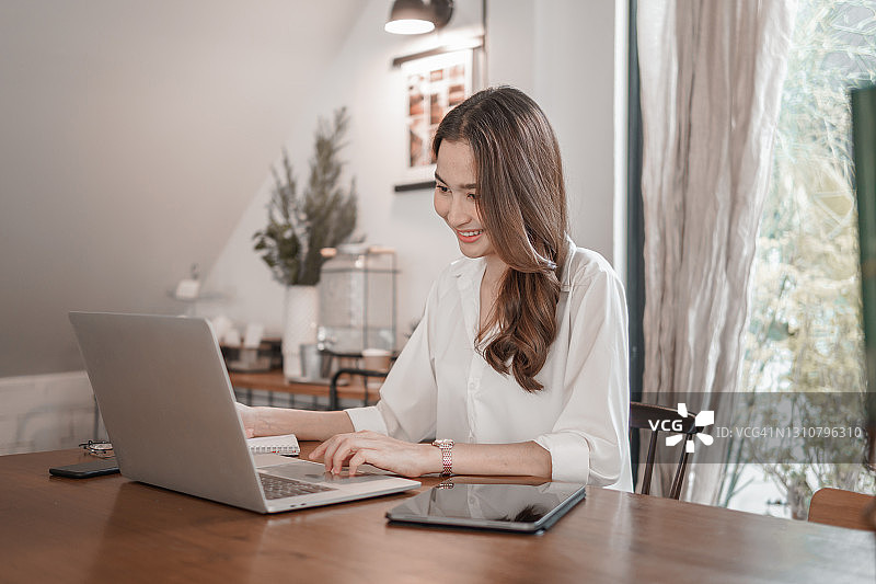 微笑的女人使用笔记本电脑键盘专业工作图片素材