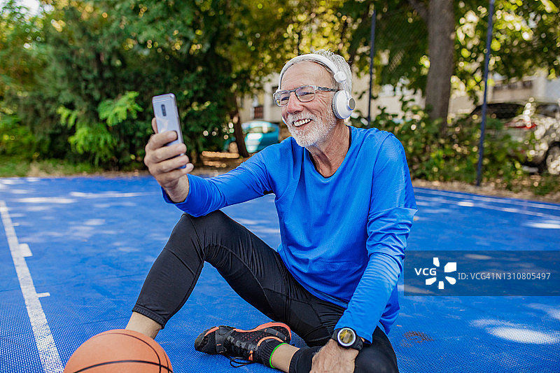 在篮球场上使用手机的活力老年男人图片素材