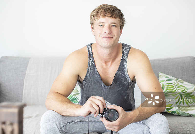 成年男子在家中沙发上拿着相机的肖像图片素材