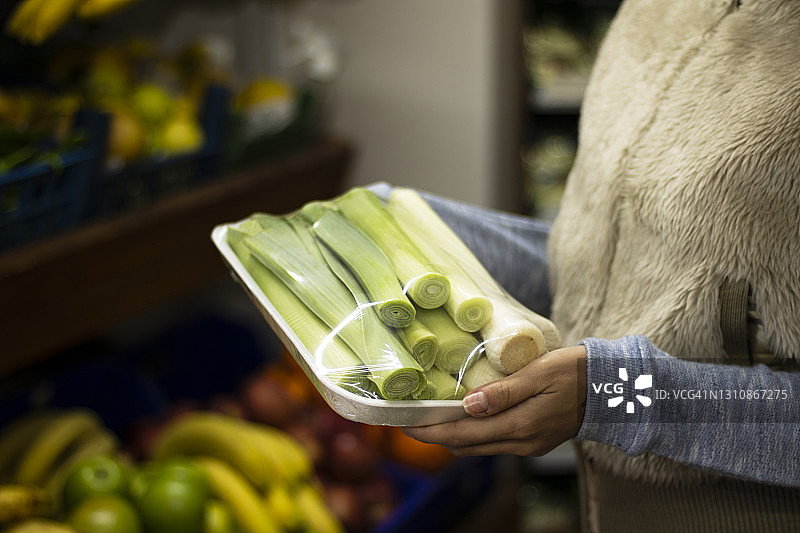 在超市蔬菜区查看牛奶标签的女人图片素材