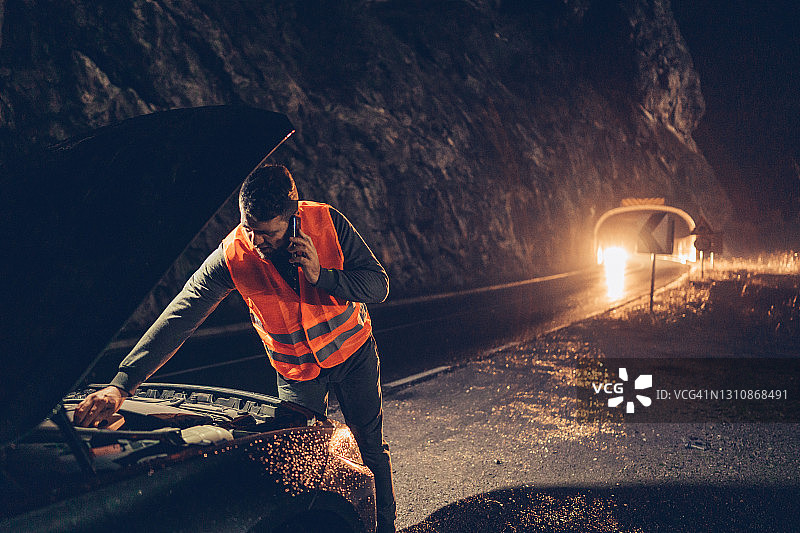男人穿反光背心在路边检查汽车引擎盖图片素材