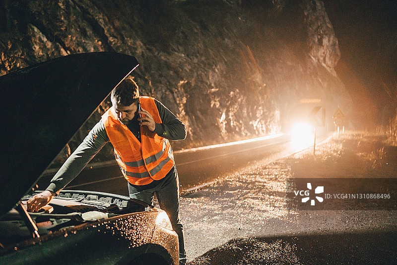 男人穿反光背心在路边检查汽车引擎盖图片素材