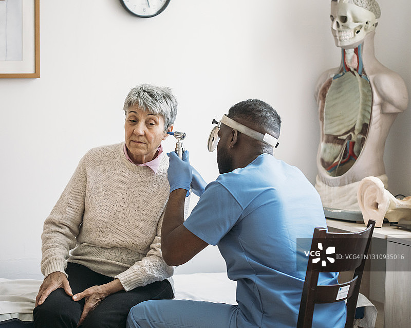 中年妇女在常规医疗检查时接受医生检查耳朵图片素材