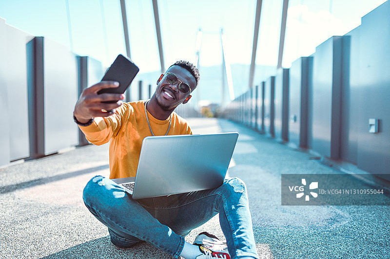 在笔记本电脑上工作的现代非洲男人自拍图片素材