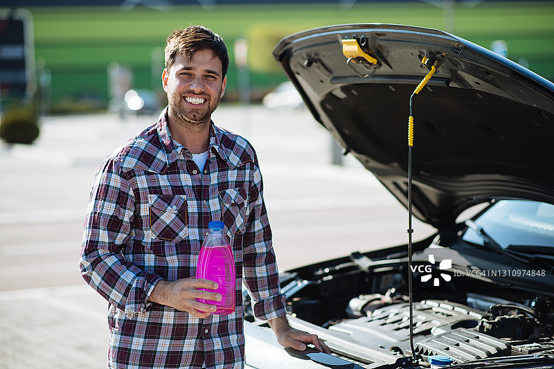 男人往汽车里倒入防冻液或冷却液，看着镜头图片素材