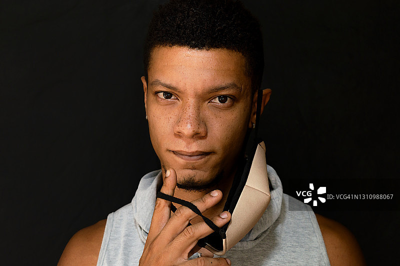 摘下面具时面带微笑的年轻拉丁裔男子图片素材